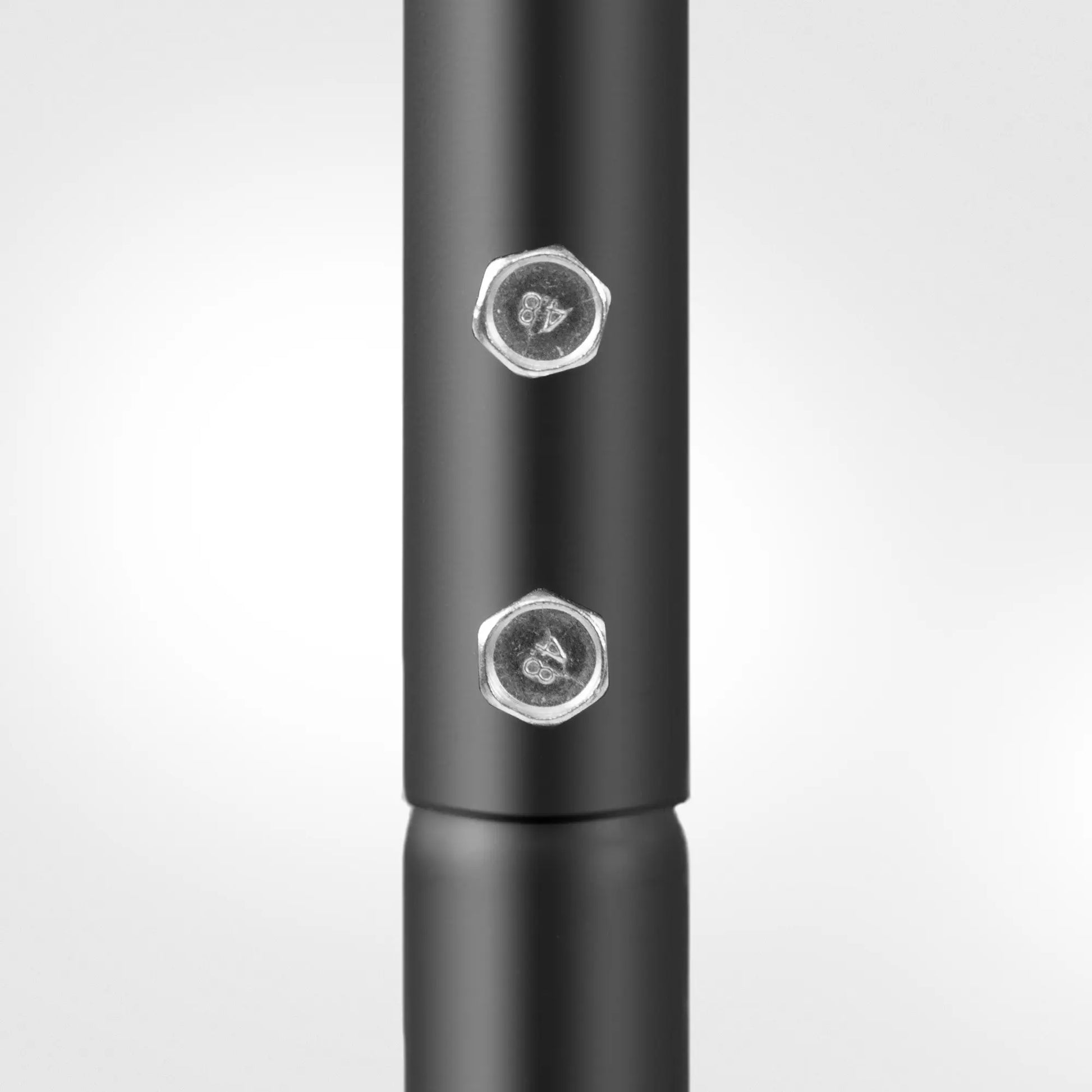 Close-up of a black metal rod with two hexagonal nuts on a white background