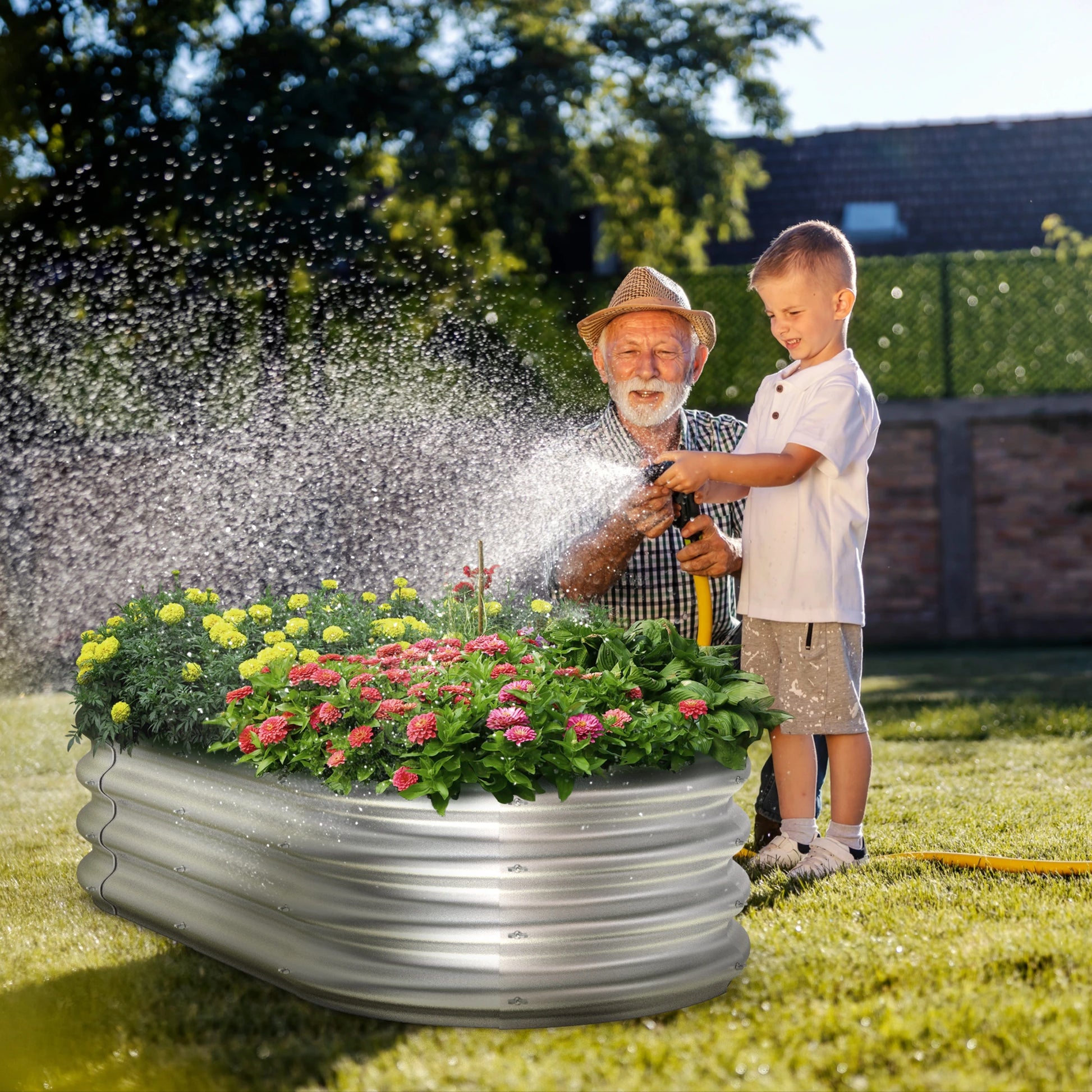 A man and a child are watering flowers in a Dwellcozy metal garden bed outdoors.