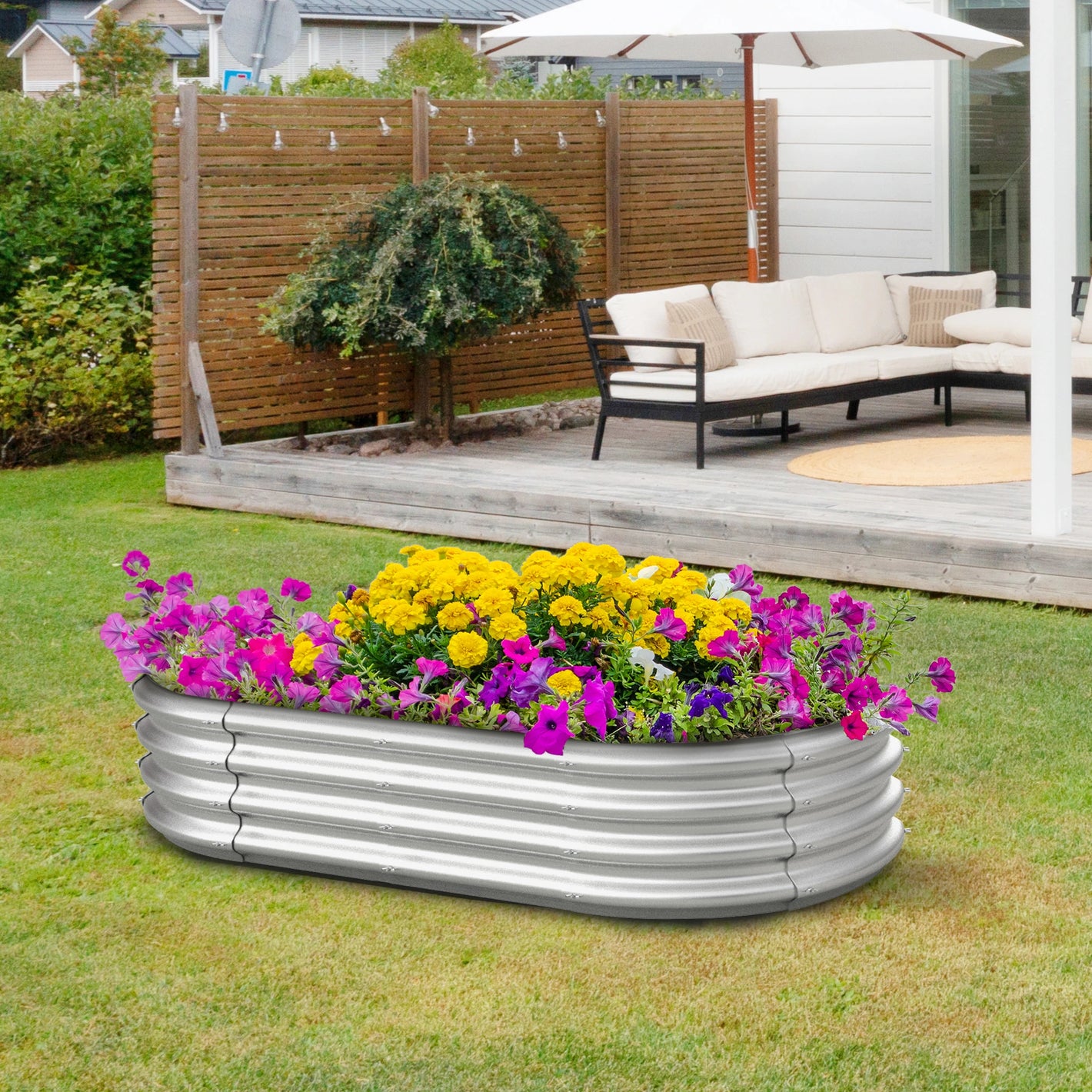 Dwellcozy metal garden bed with colorful flowers in a garden.