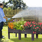 Person watering flowers in a raised garden bed with a hose.